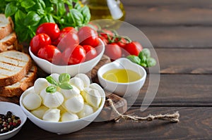 Italian food ingredients Ã¢â¬â mozzarella, tomatoes, basil and olive oil on rustic wooden table.